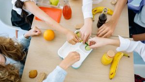 Children enjoying a variety of healthy snacks and drinks at a shared table, top view.