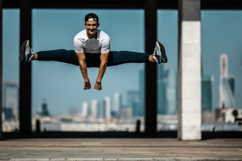 Man performing a split jump on concrete, showcasing fitness and agility.
